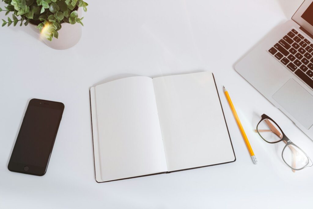 Escritorio blanco con notas, teléfono y laptop, preparado para hacer un diagnóstico de marketing paso a paso